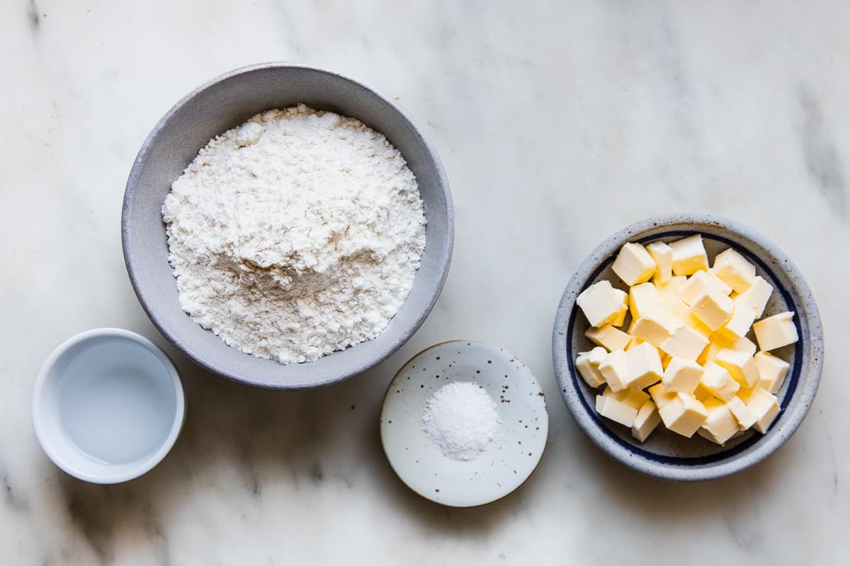 flour, butter, salt and ice water in bowls on the counter to make easy all-butter pie crust