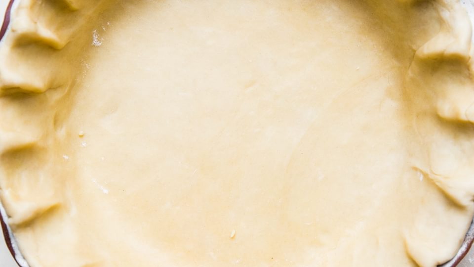 unbaked homemade Easy all-butter pie crust pressed in a pie pan on the counter