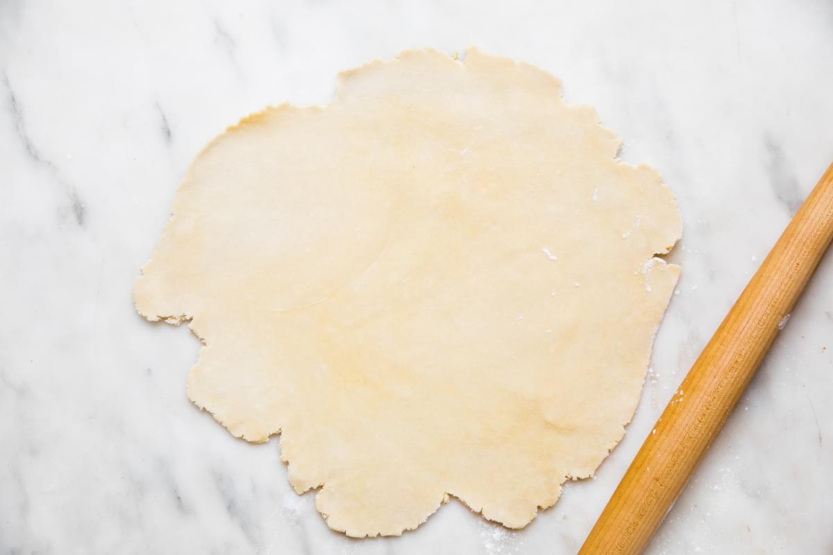 homemade easy all-butter pie crust rolled out on the counter next to a rolling pin