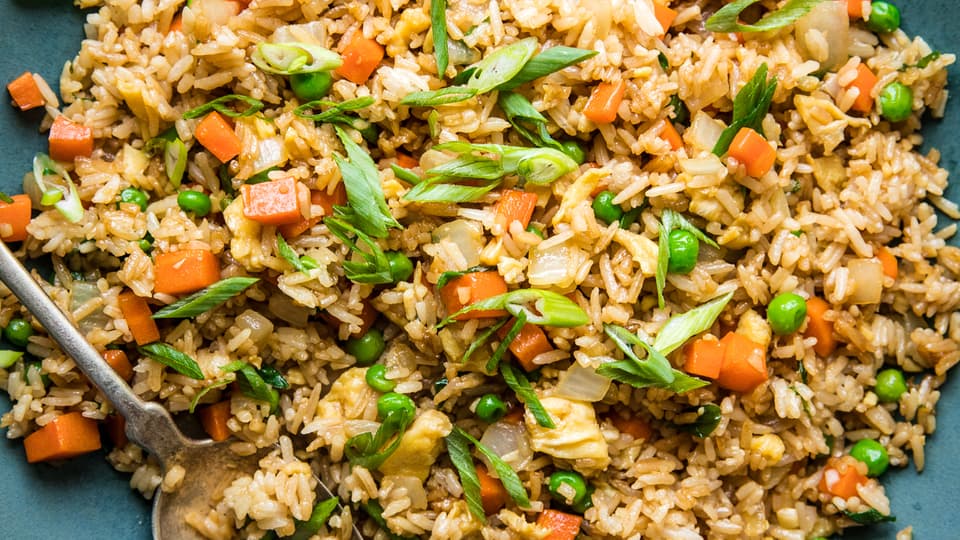 homemade fried rice in a bowl with peas, carrots, onion and egg