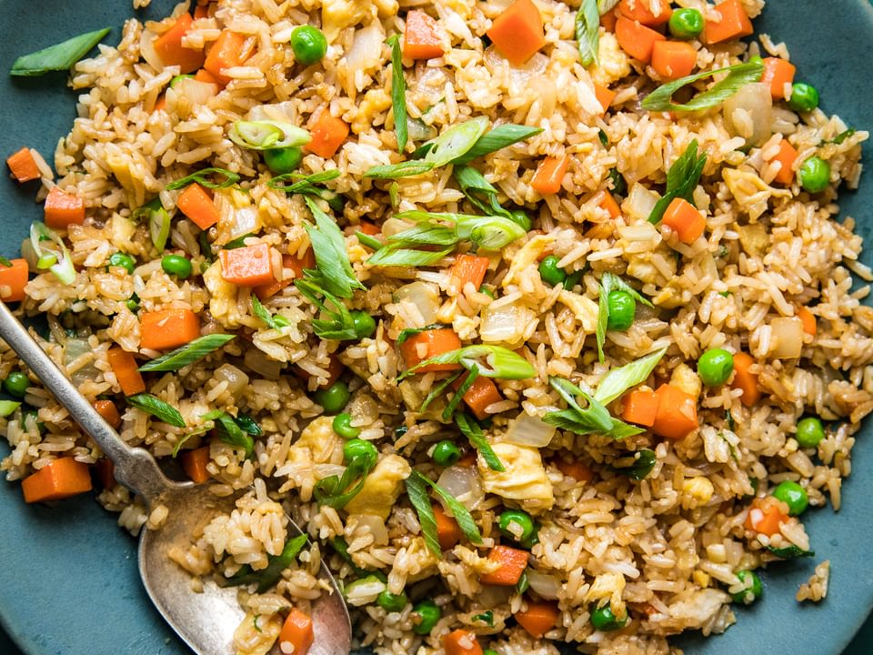 homemade fried rice in a bowl with peas, carrots, onion and egg