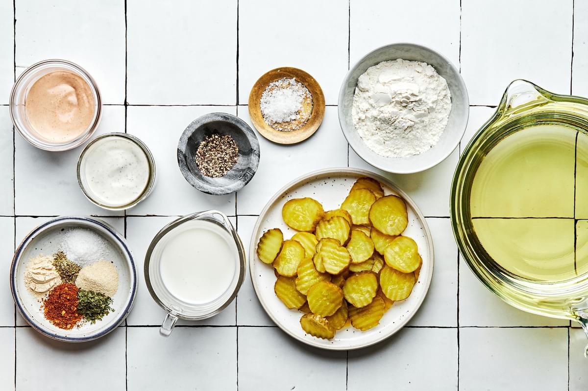pickles, flour, cajun seasoning, parsley, oregano, salt, garlic powder, onion powder, buttermilk and vegetable oil in bowls