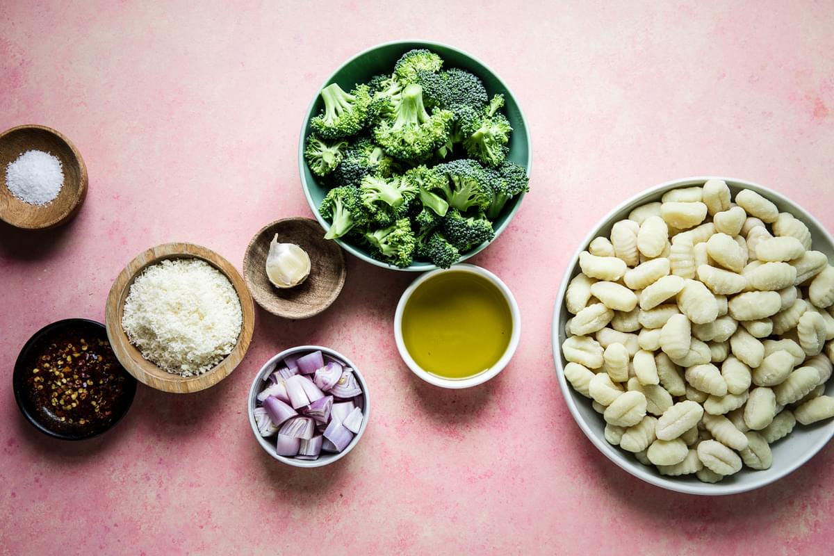 Gnocchi in a bowl, broccoli in a bowl, olive oil, red onion, parmesan, salt, garlic and pepper