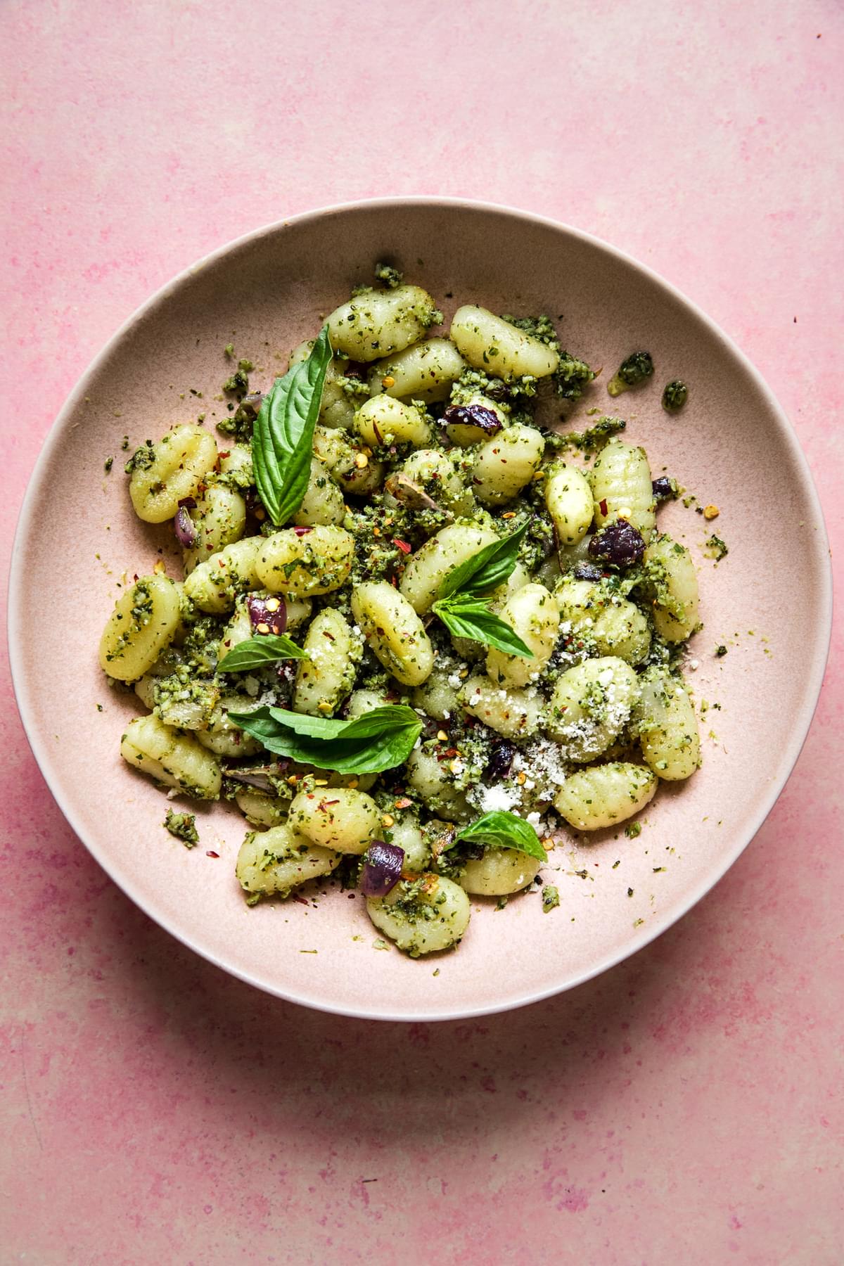 Roasted broccoli pesto gnocchi with red onions in a bowl