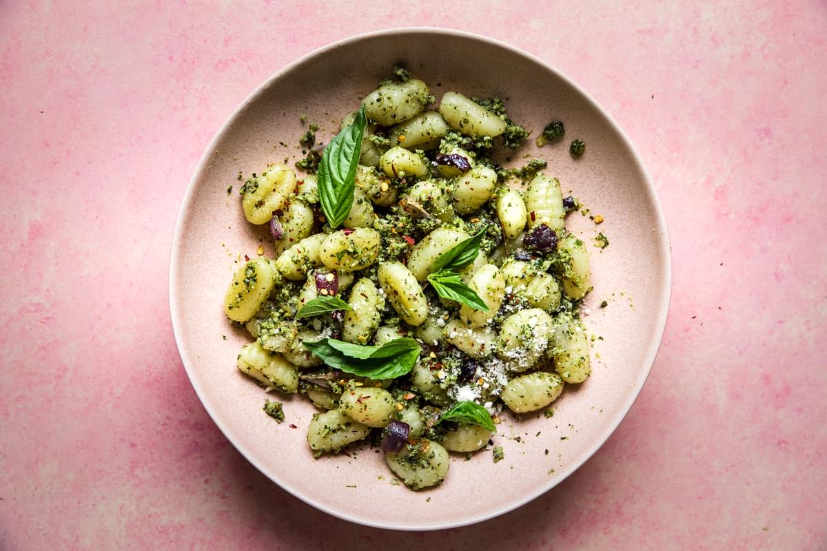 Roasted broccoli pesto gnocchi with red onions in a bowl