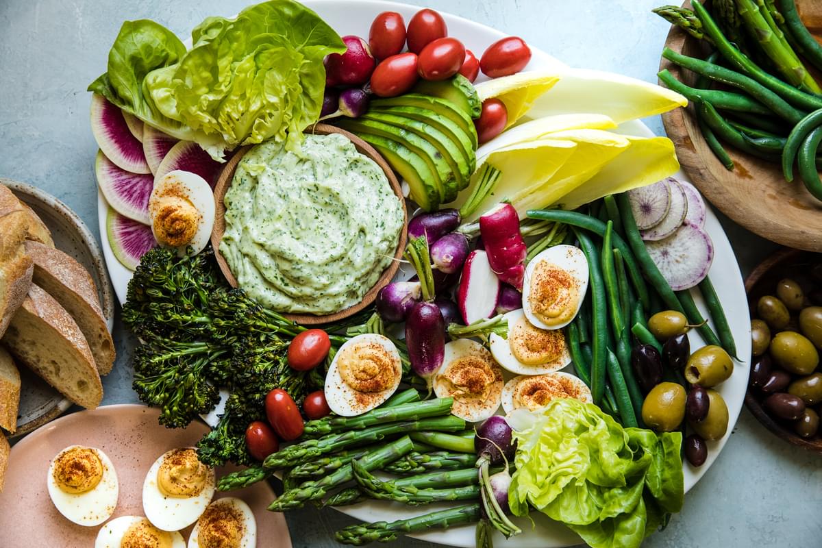 grand aioli on a plater with blanched, raw, roasted and grilled vegetables on a plate green goddess dip