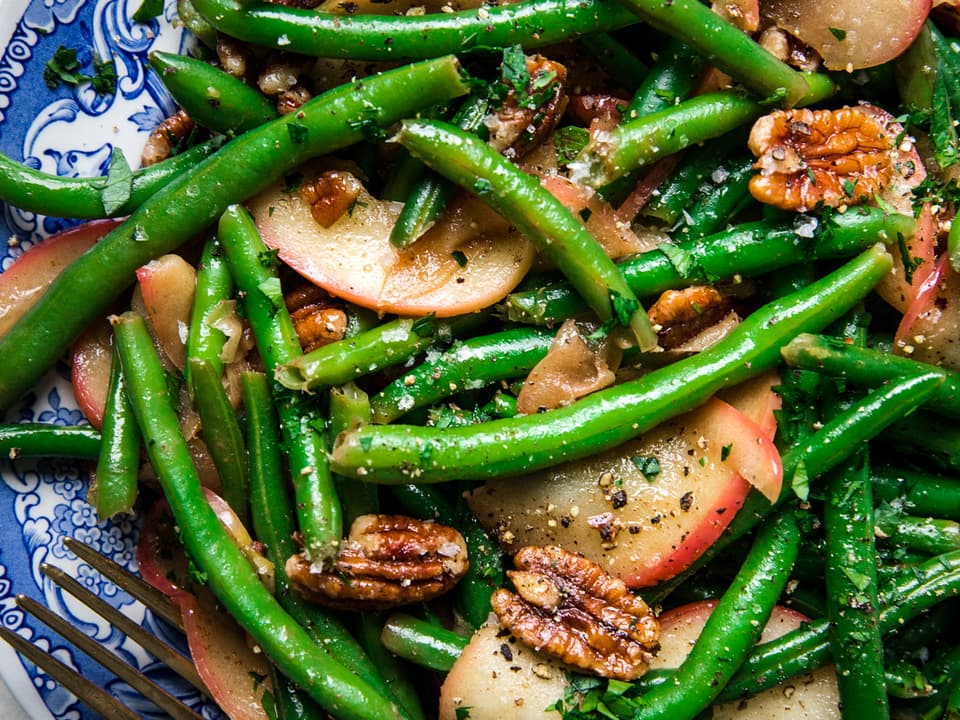 Homemade Green Beans with Apples and Sage Butter on a serving plate with a serving fork
