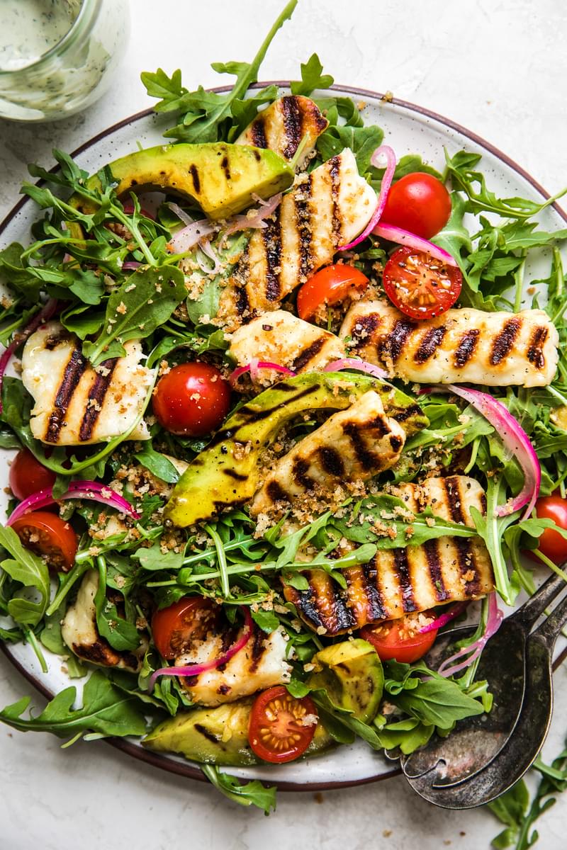 Grilled halloumi Salad with avocado, pickled onions, arugula and cherry tomatoes with a creamy basil dressing