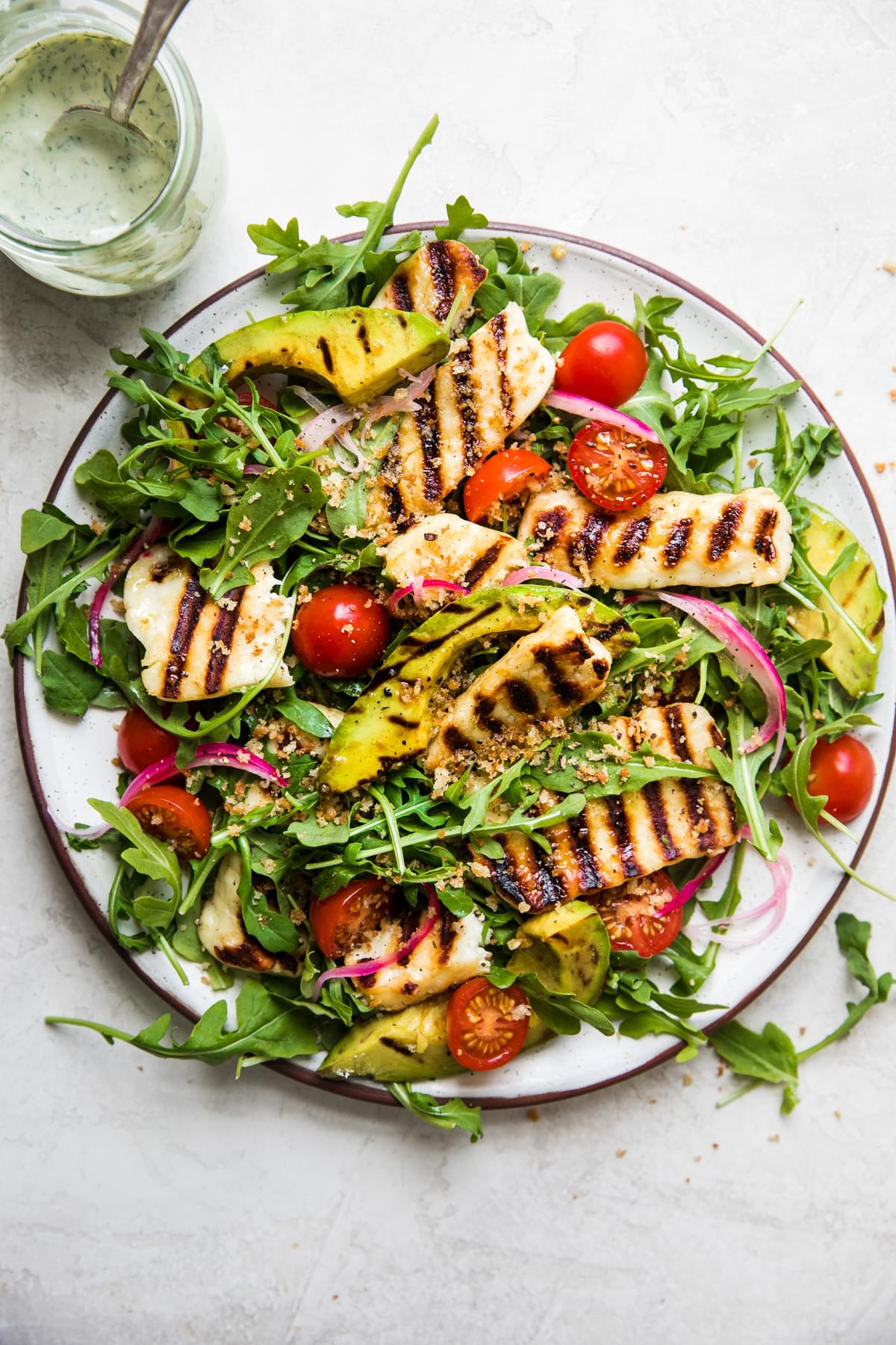 Grilled Halloumi Salad with arugula, pickled onions, avocado, tomatoes and creamy basil dressing