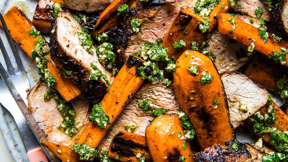 Grilled Pork Tenderloin with Carrots and Chermoula on a plate with a fork and knife