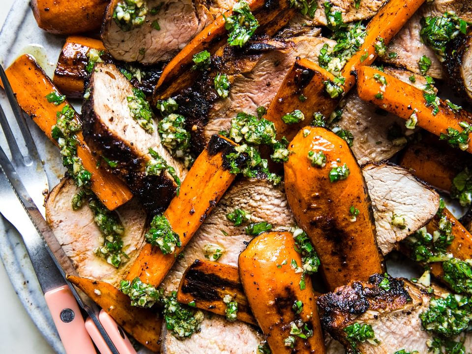 Grilled Pork Tenderloin with Carrots and Chermoula on a plate with a fork and knife