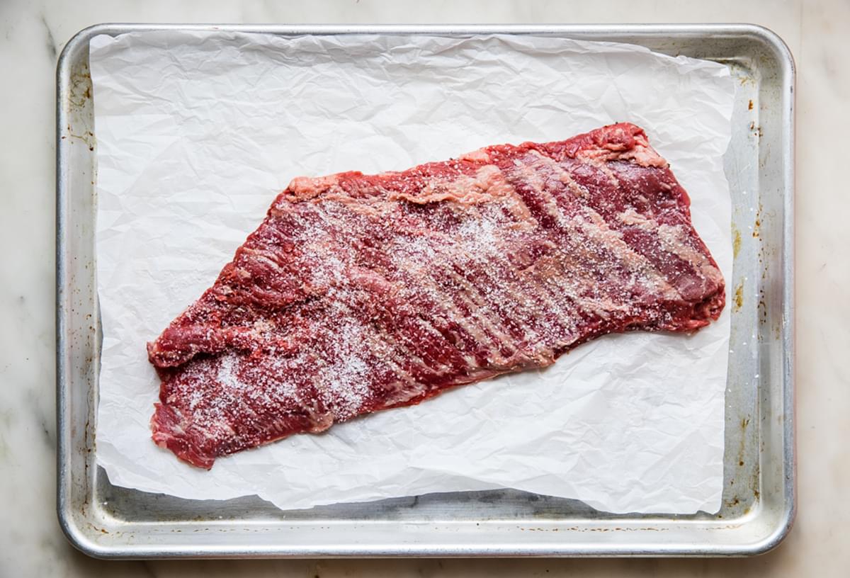 raw skirt steak with salt on parchment paper
