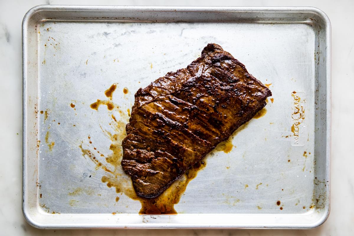 grilled skirt steak resting on a baking sheet