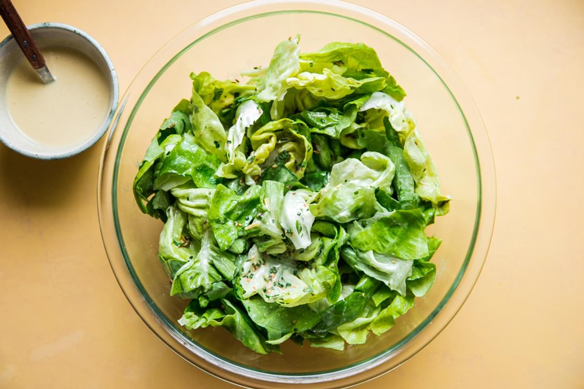 Herby Seedy Butter Lettuce Salad with Tahini Dressing in a bowl with a side of dressing