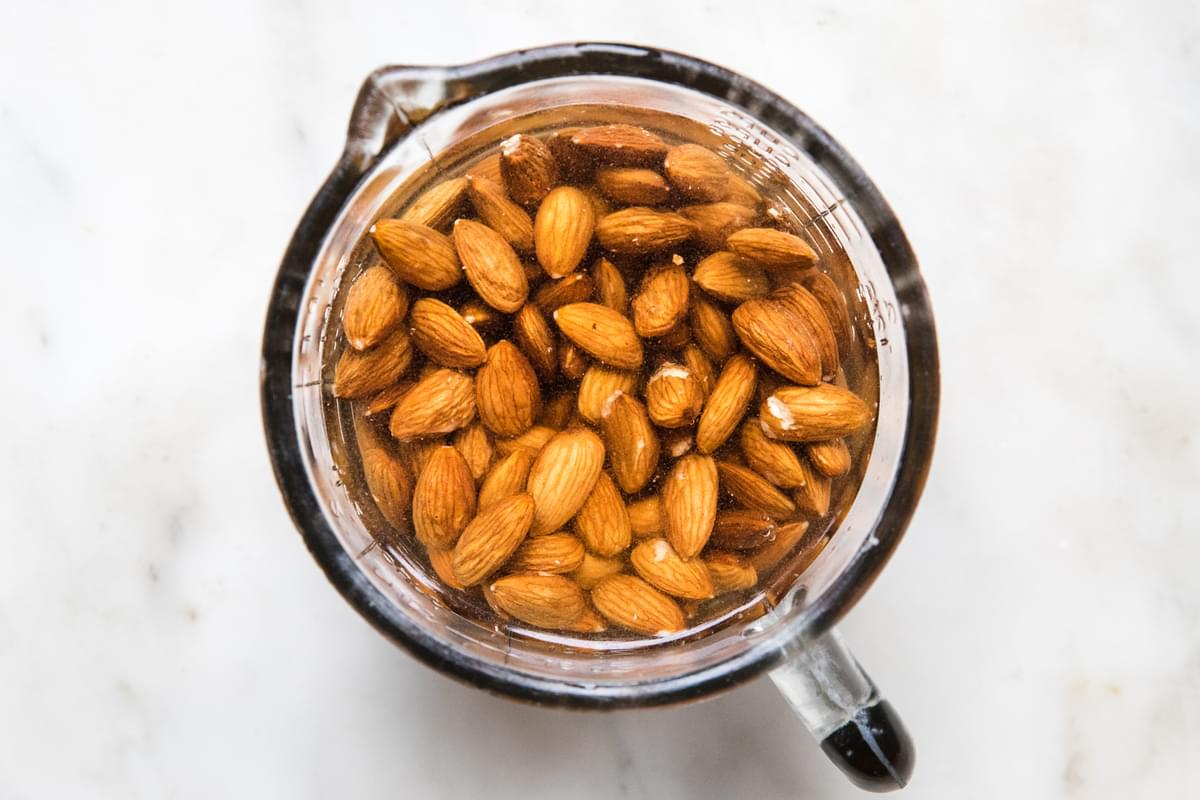 almonds soaking in water in a glass measuring bowl
