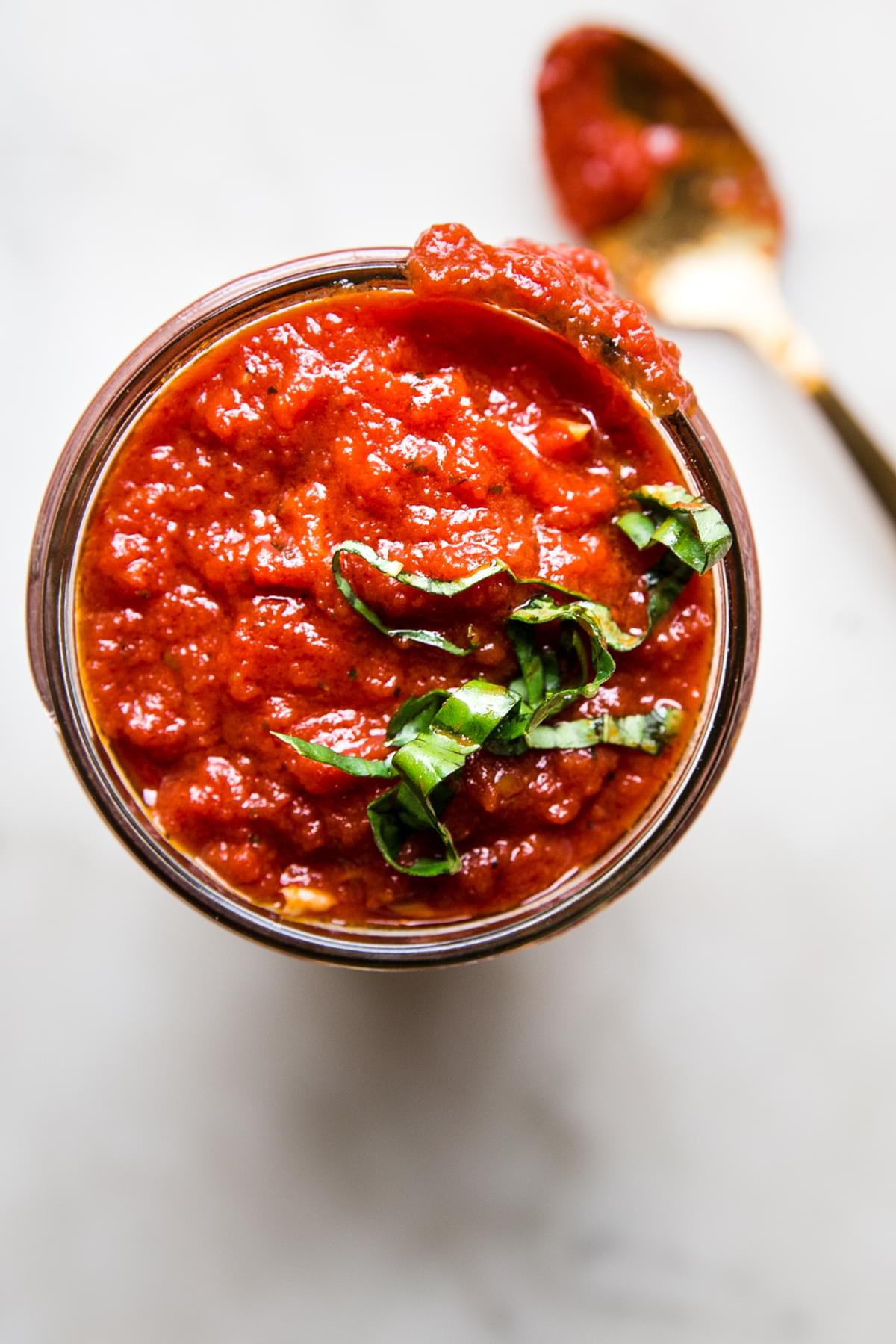 Homemade Marinara Sauce in a jar with fresh basil and a spoon