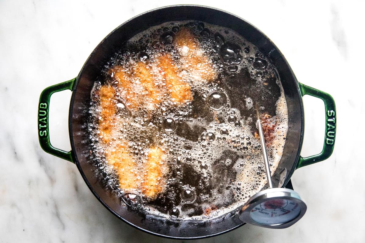 homemade mozzarella sticks being deep fried in a pot of oil