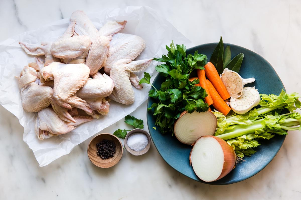 homemade chicken stock ingredients. onion, celery, garlic, chicken wings, salt, pepper, bay leaf and parsley.