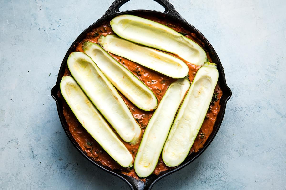 creamy tomato sauce in a skillet with zucchini boats