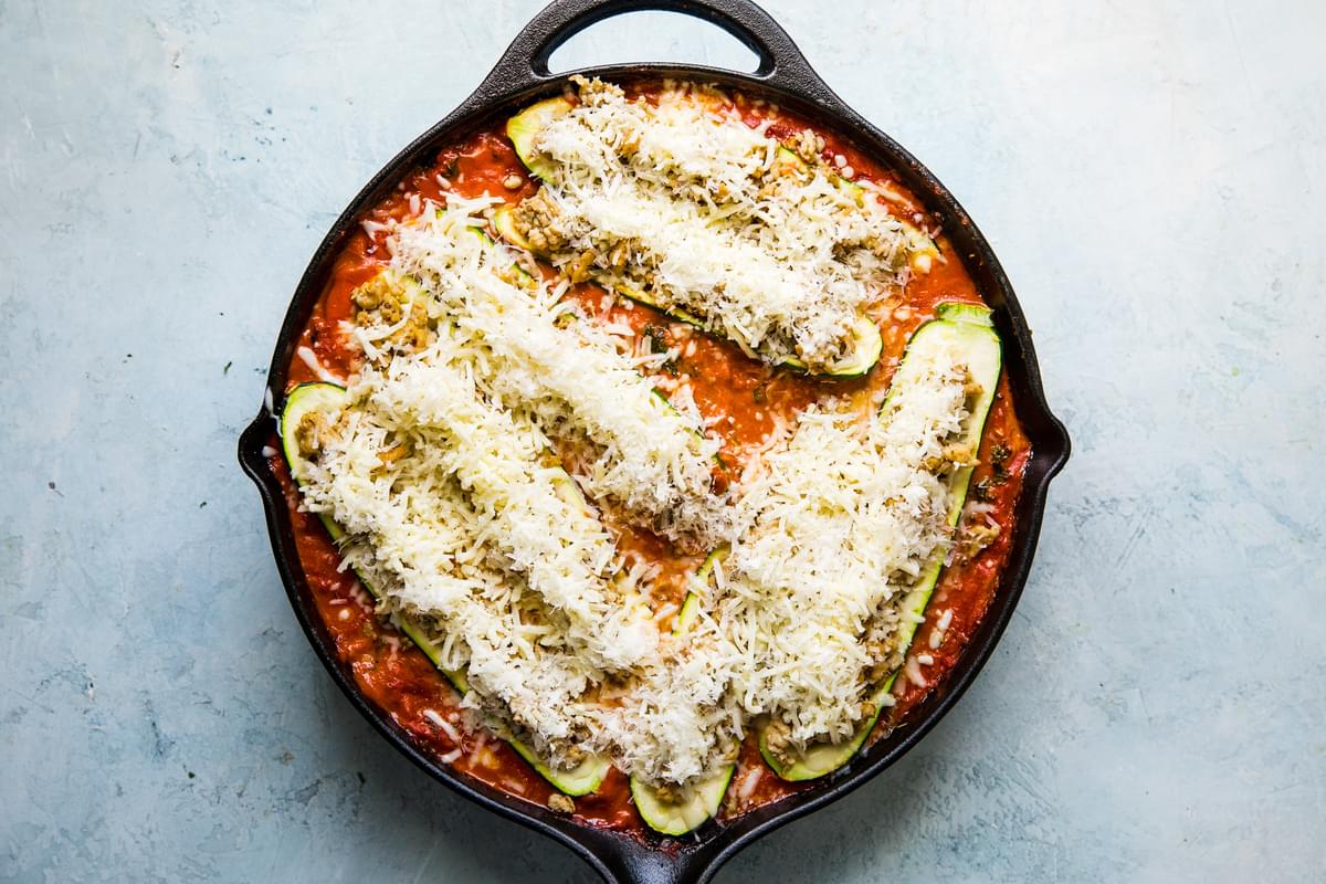 zucchini boats with ground chicken, spices and parmesan cheese in a creamy tomato sauce in a skillet