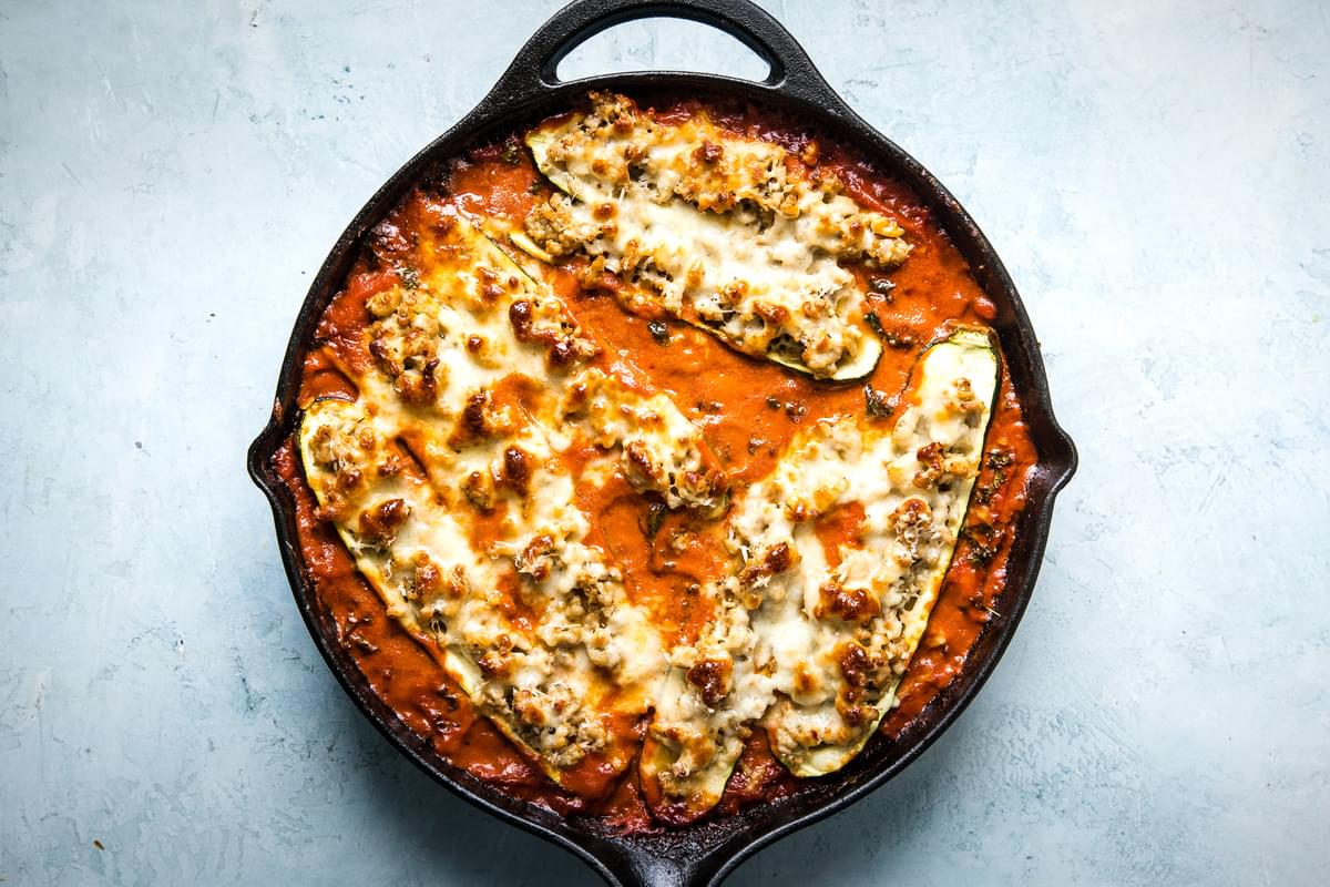 zucchini boats with ground chicken, spices, parmesan cheese and mozzarella in a creamy tomato sauce in a skillet