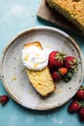 Olive Oil Cake made with lemon topped with whipped cream and berries on a plate