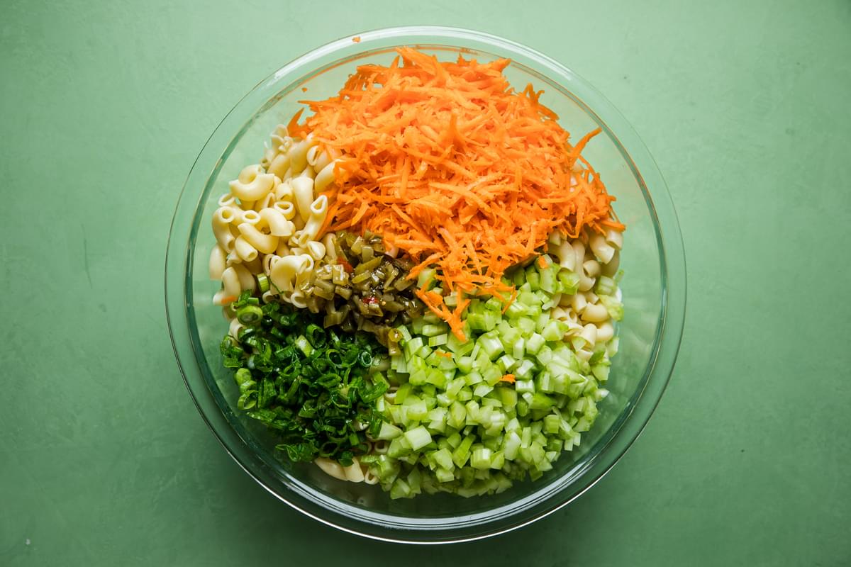cooked pasta, carrots, relish, green onions and celery in a bowl for pasta salad