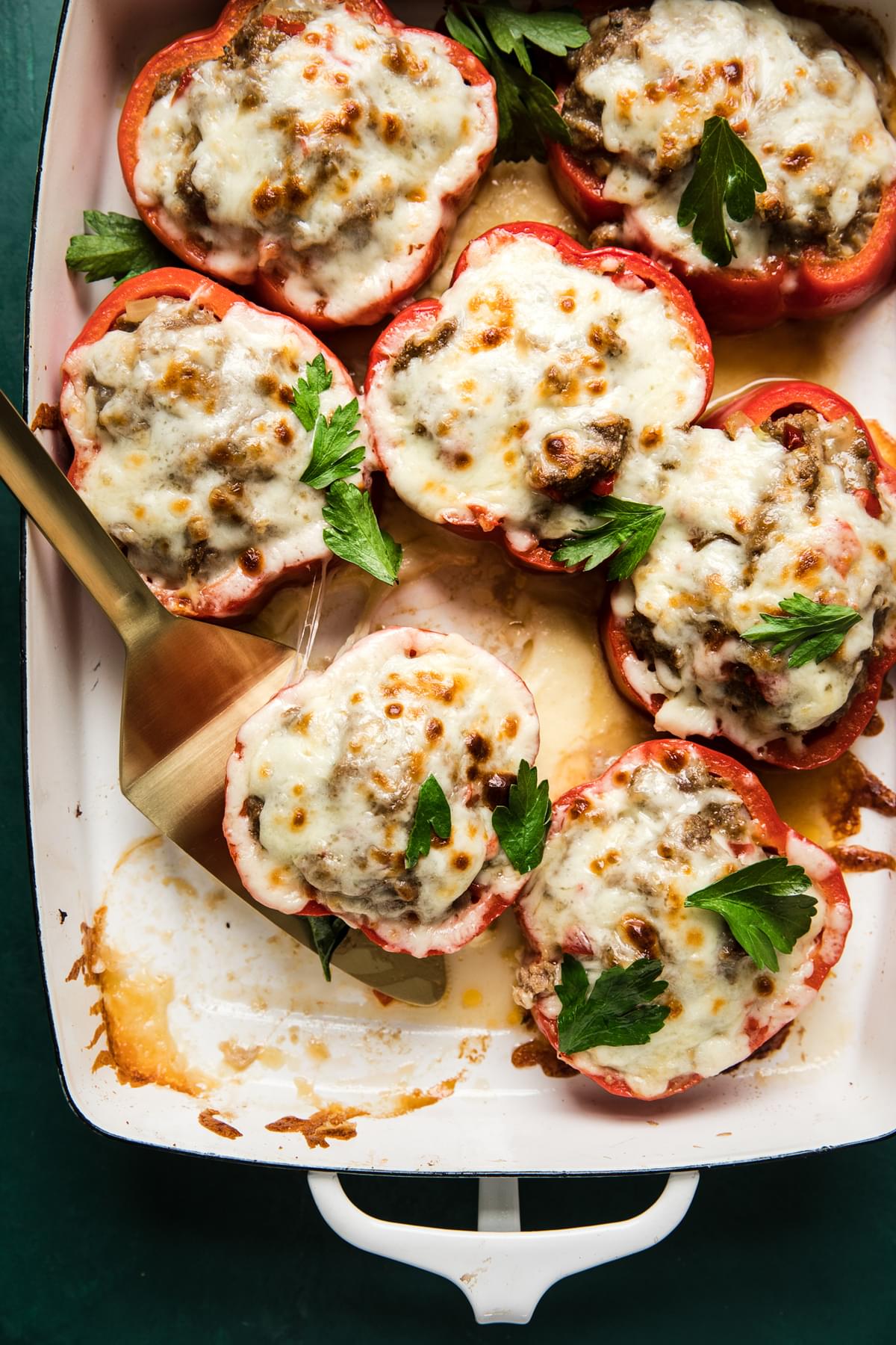 Homemade Stuffed Peppers topped with melted cheese and parsley garnish in a baking dish