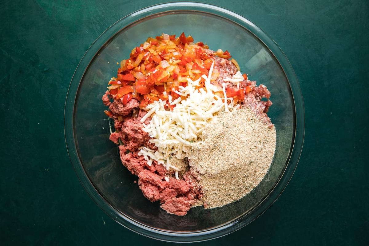 ground beef, sausage, bell peppers, garlic and cheese for stuffed peppers in a mixing bowl