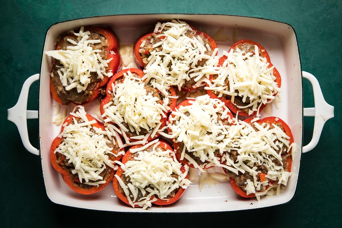 bell pepper rings filled with meatball filling topped with cheese in a 9x 13 baking dish