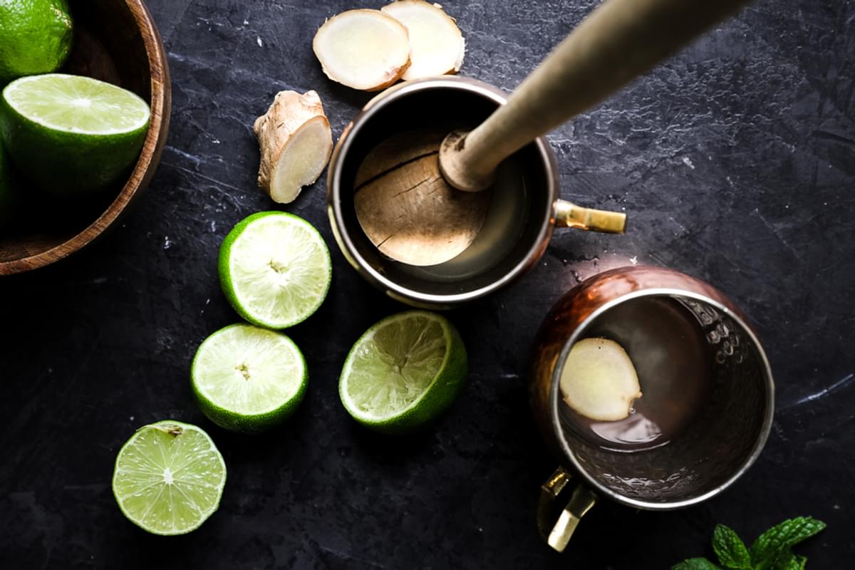 two copper mugs with muddled ginger and limes