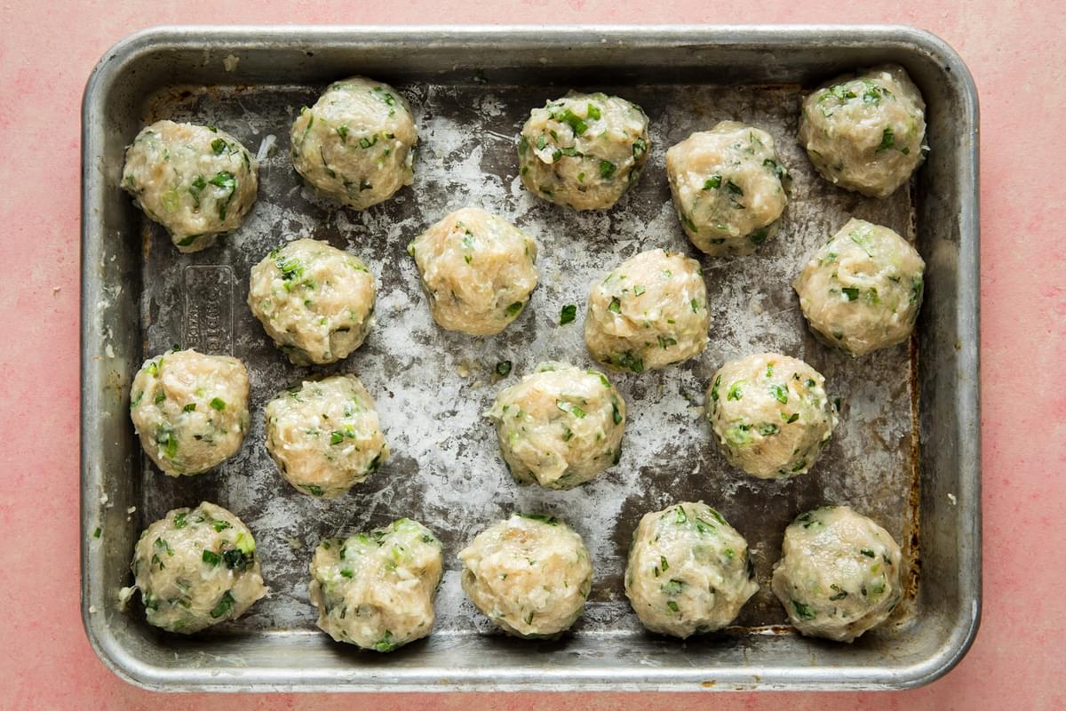 raw home made chicken meatballs on a baking sheet
