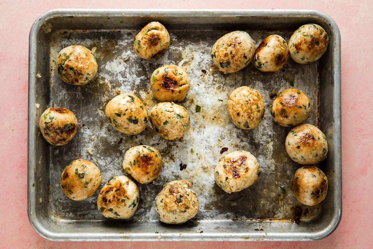 browned homemade chicken meatballs on a baking sheet