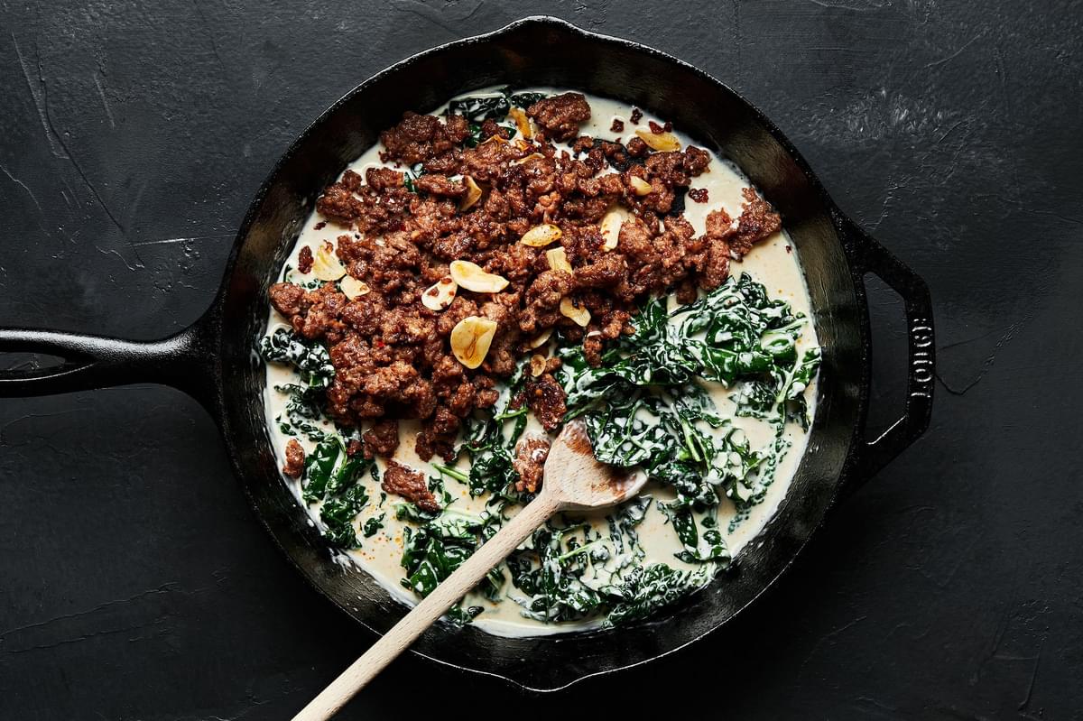 cream sauce with kale, garlic and sausage in a cast iron skillet