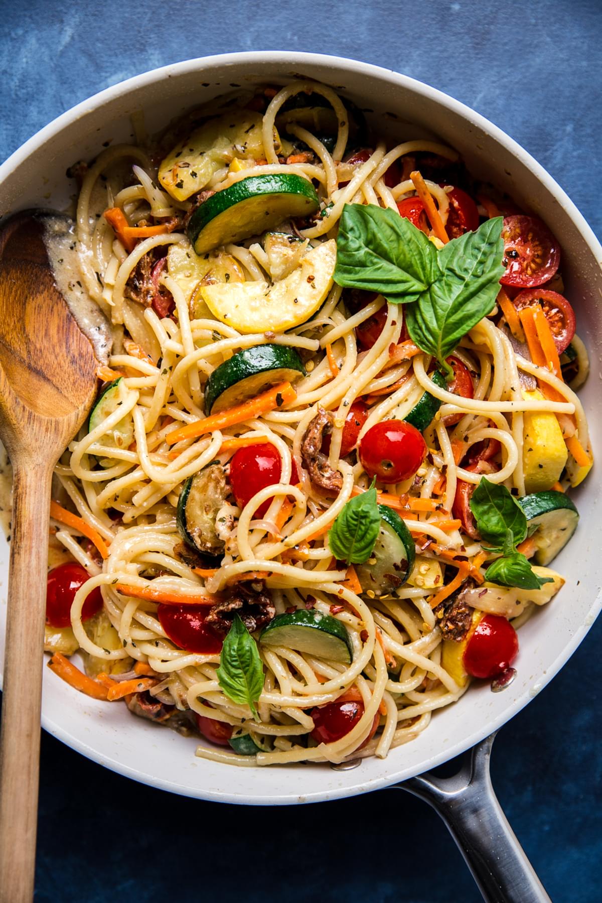homemade pasta primavera in a skillet with a wooden spoon