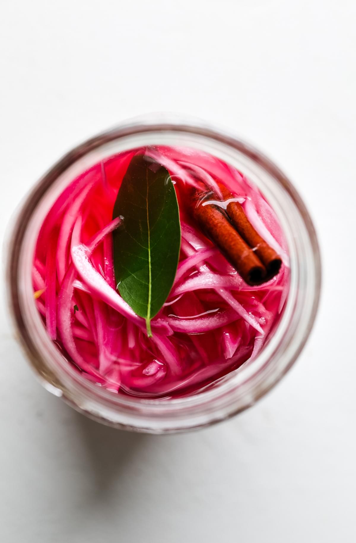 homemade pickled red onions in a jar with bay leaf, cinnamon
