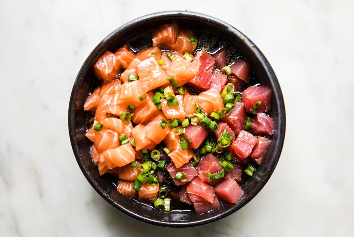 sushi grade tuna and salmon in a bowl with green onions, sesame oil, rice vinegar and ginger