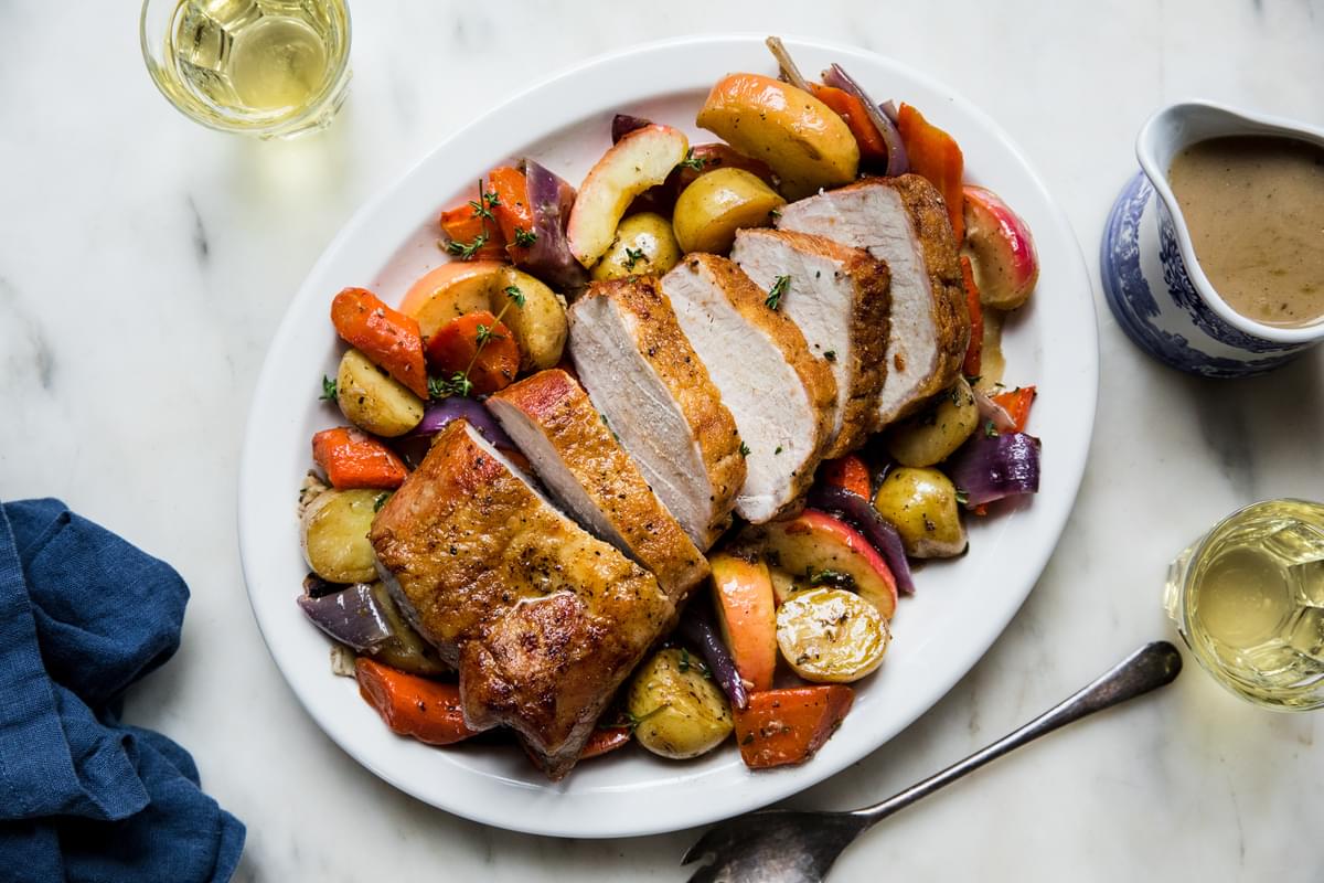 Pork Loin Roast with roasted apples and carrots and potatoes and finished with a cider gravy on a serving platter