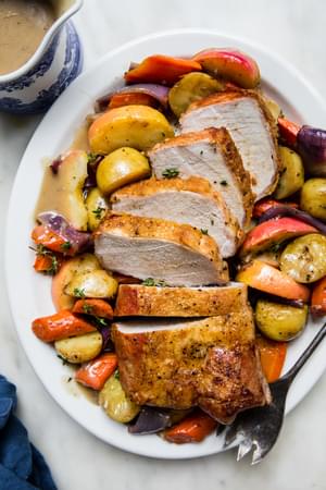 Pork Loin Roast with roasted apples and root veggies and finished with a cider gravy on a serving platter
