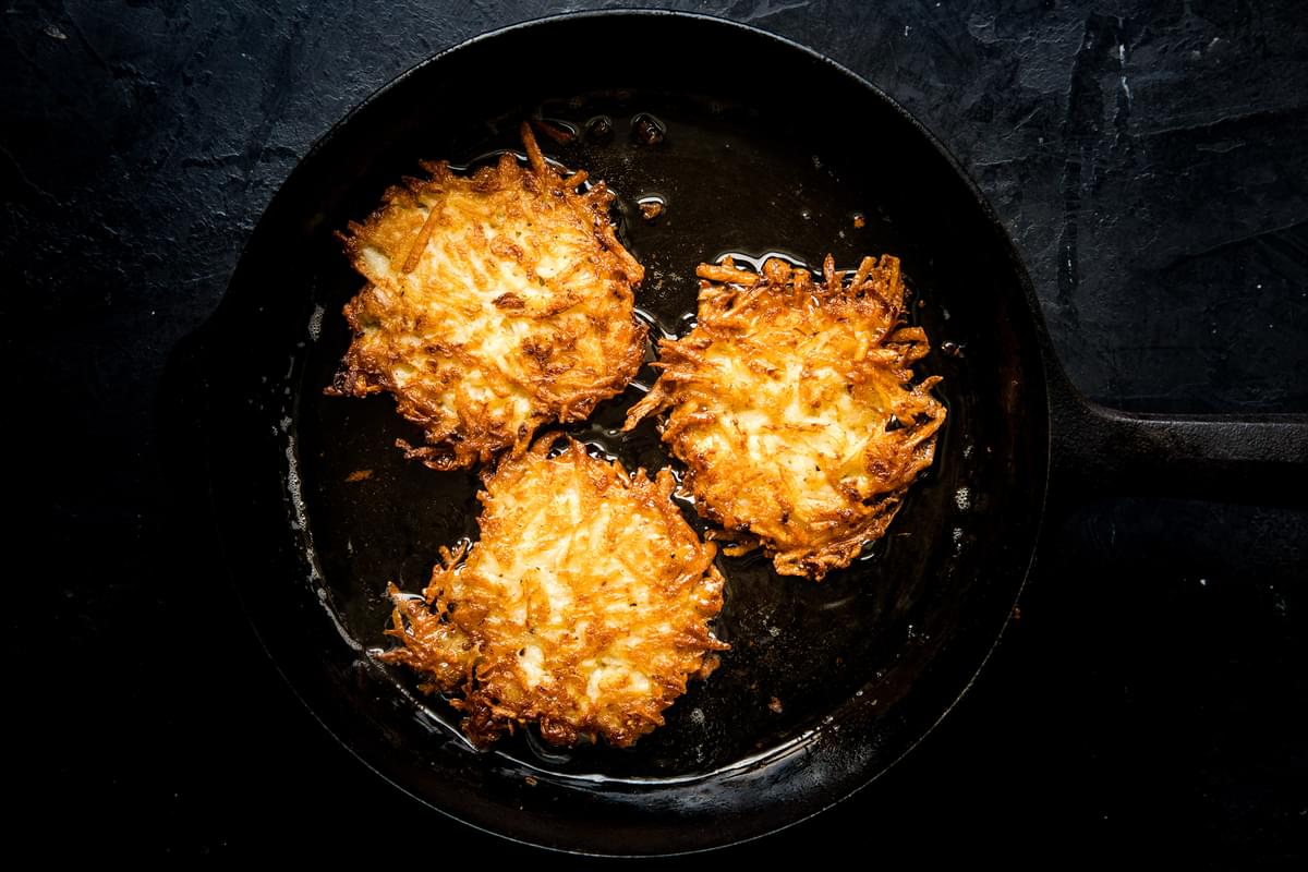 homemade potato pancakes being fried in a skillet