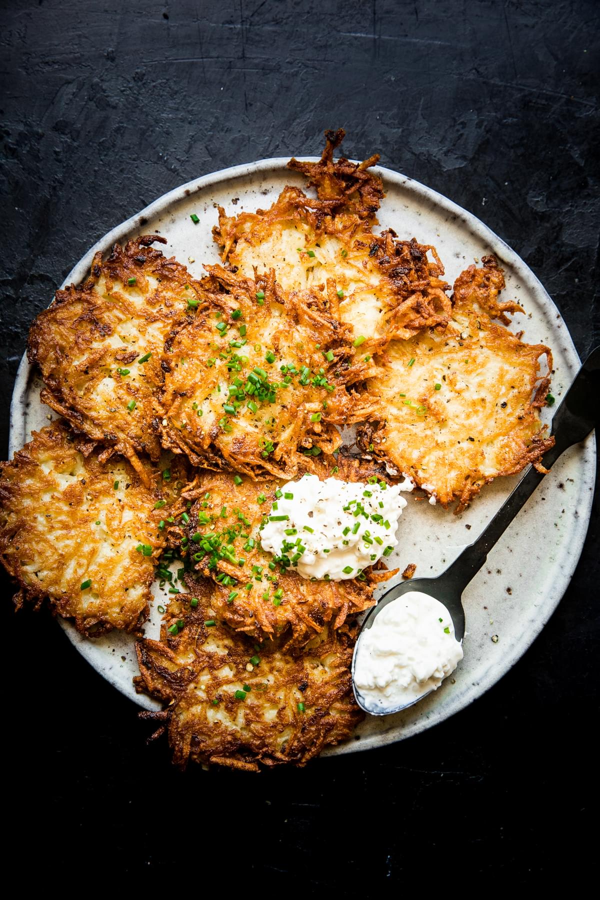 homemade potato pancakes on a plate topped with a dollop of sour cream