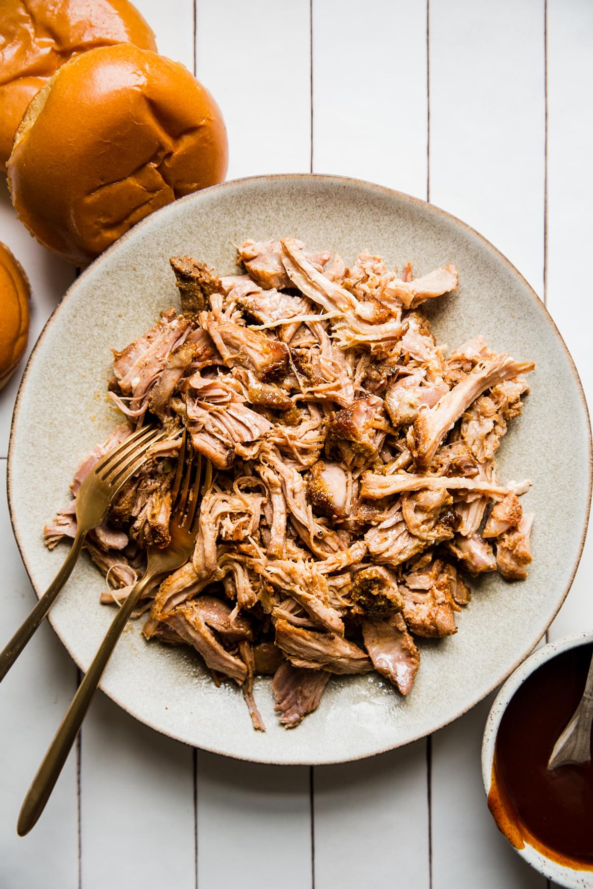 shredded pork shoulder cooked with spices, chicken stock, and vinegar. Shredded and mixed with bbq sauce on a plate.