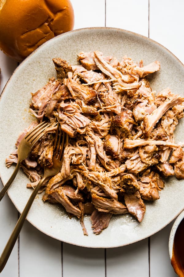 homemade pulled pork recipe shredded on a plate with two forks