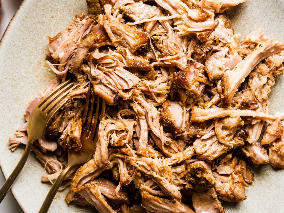 homemade pulled pork recipe shredded on a plate with two forks