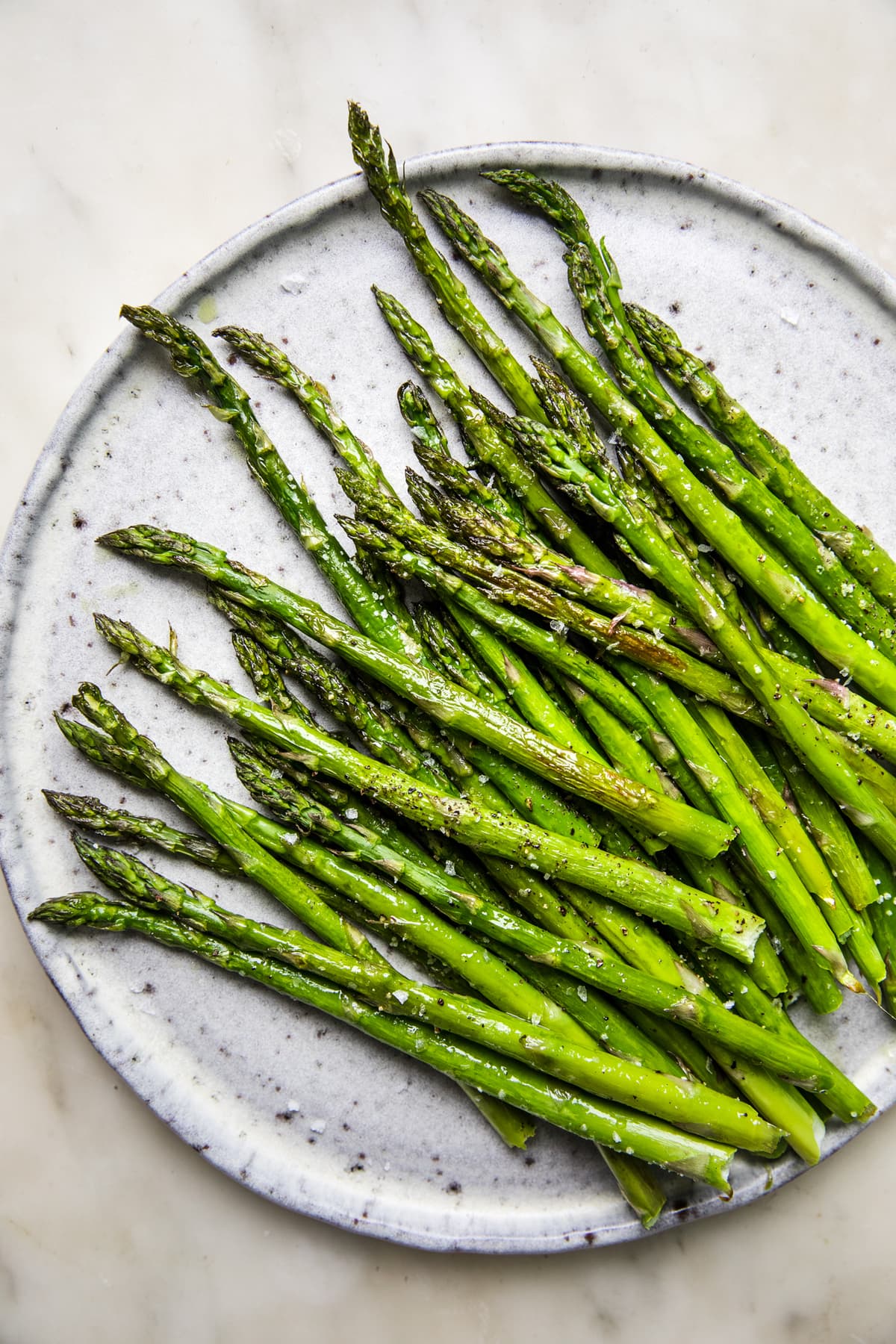 Roasted Asparagus seasoned with olive oil, salt and pepper on a serving plate on the counter