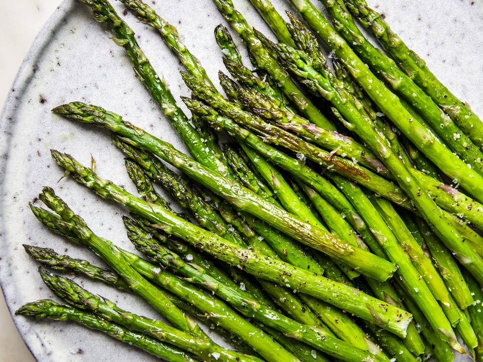 Roasted Asparagus seasoned with olive oil, salt and pepper on a serving plate on the counter