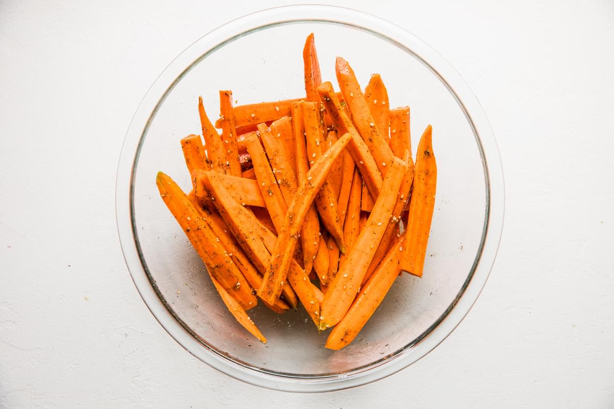 raw carrots tossed with  salt, olive oil and za’atar in a glass bowl