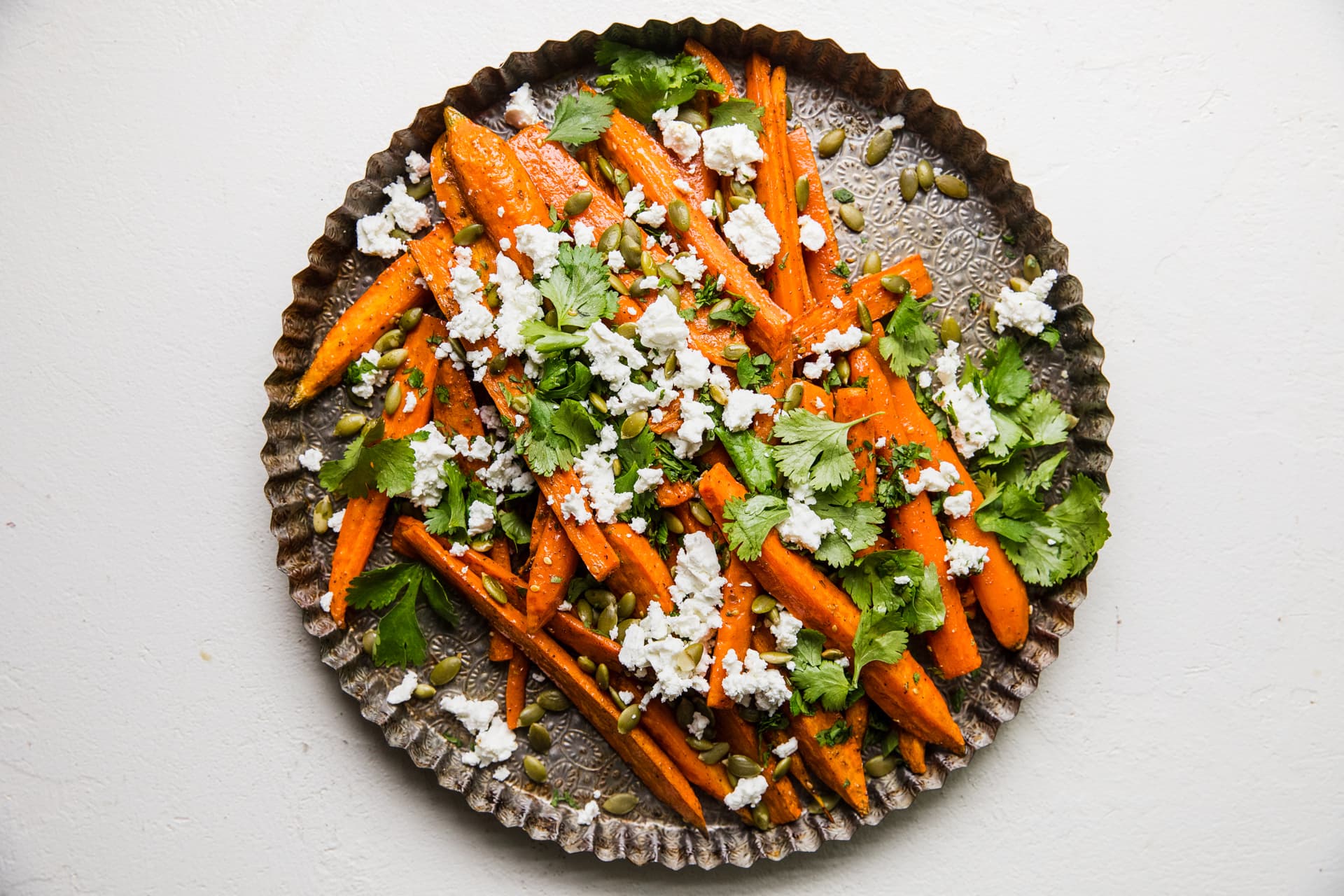 Za’atar Roasted Carrots with Feta and Pumpkin Seeds on a serving plate topped with cilantro