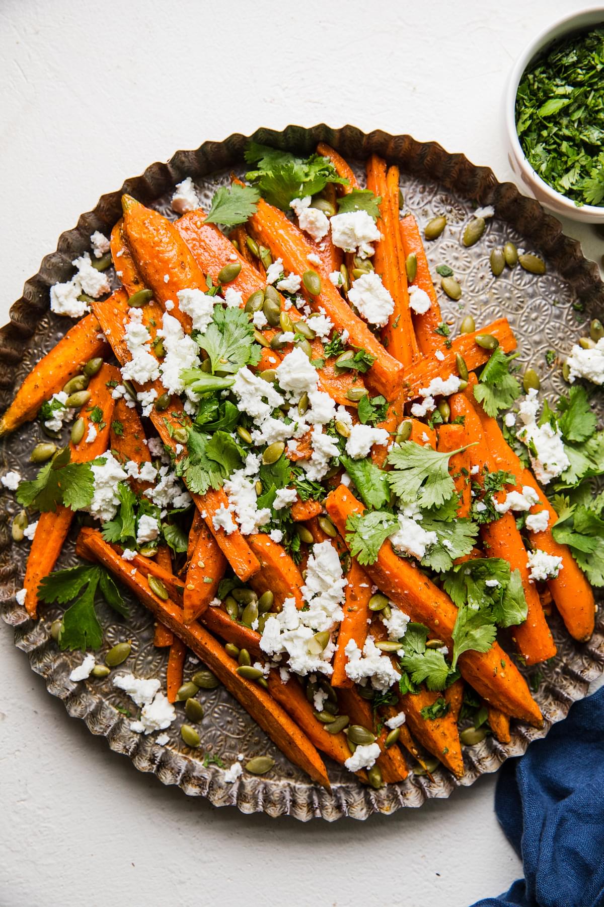 Za’atar Roasted Carrots with Feta and Pumpkin Seeds on a serving tray topped with cilantro