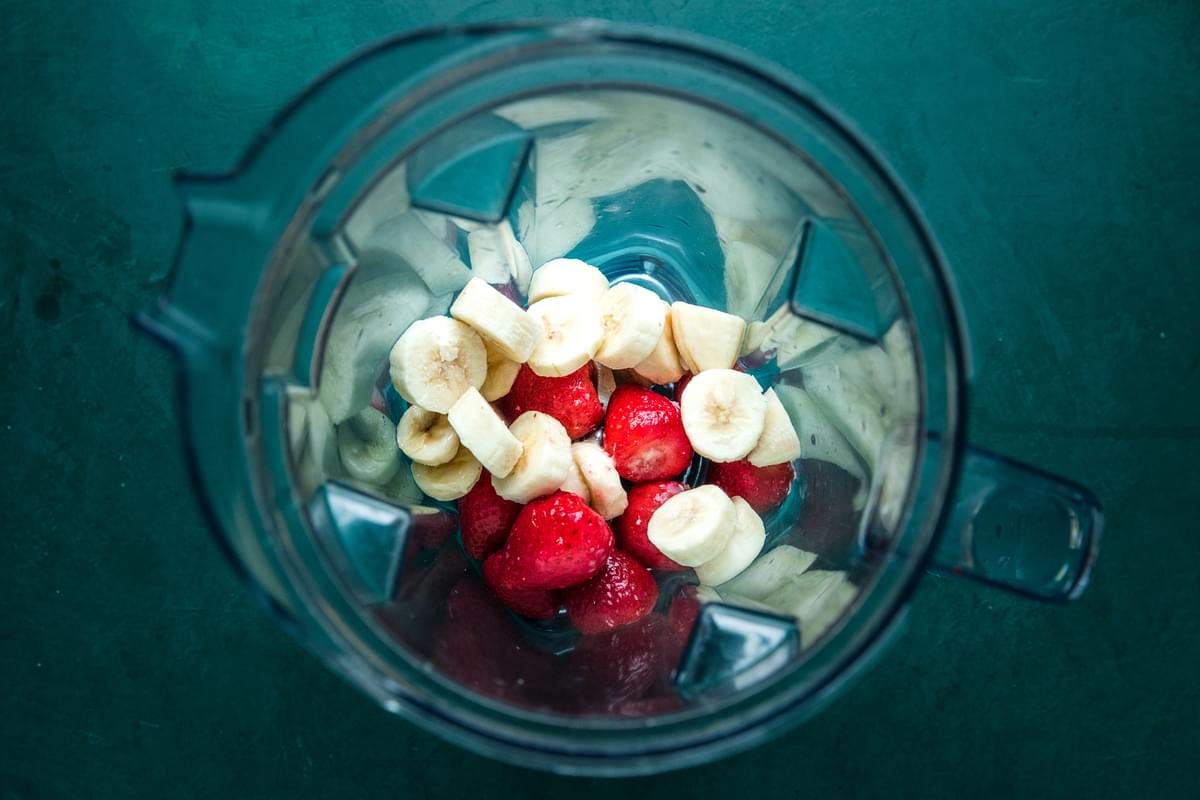 frozen pieces of strawberries and bananas in a blender